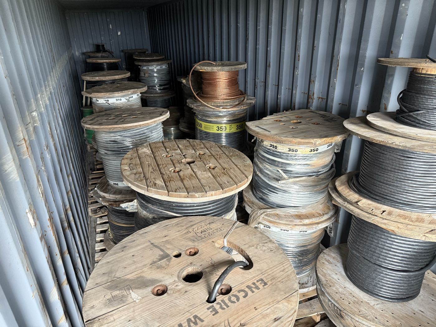Wooden reels of cable and bare copper wire inside a shipping container
