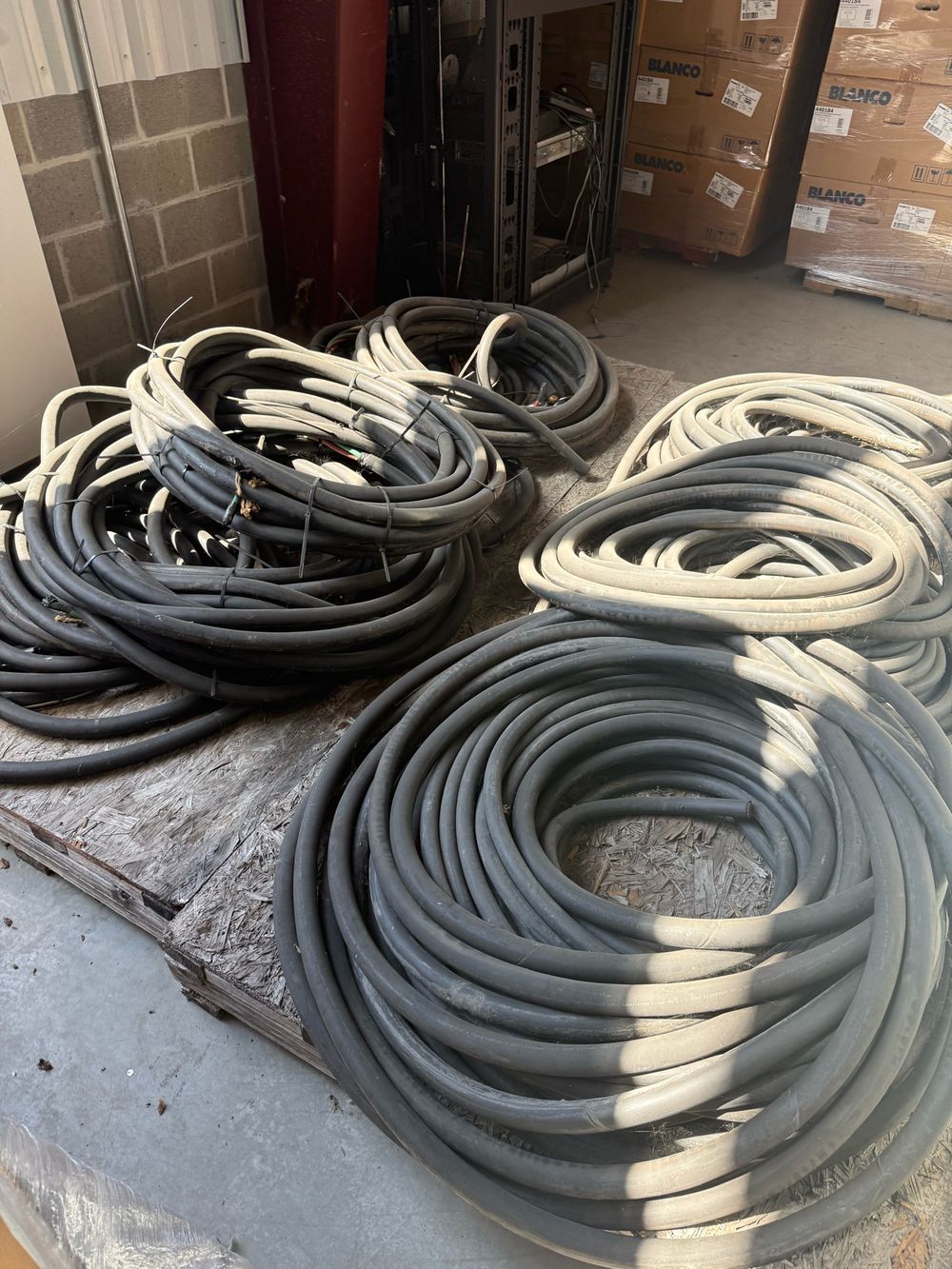 Coiled gray and black service entrance cable on a plywood floor